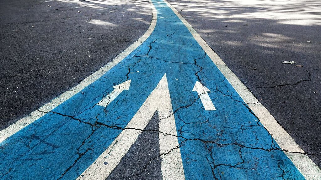 Symbolbild für Transformation: Zwei farbige Wege, die sich zu einem Weg vereinen.