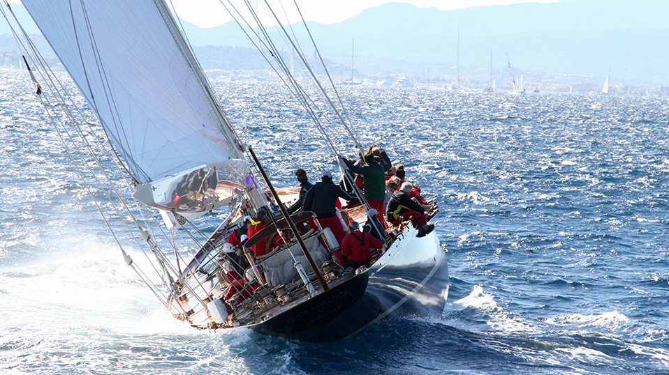 Segelboot mit Mannschaft auf hoher See bei starkem Wind, das sich zur Seite neigt.