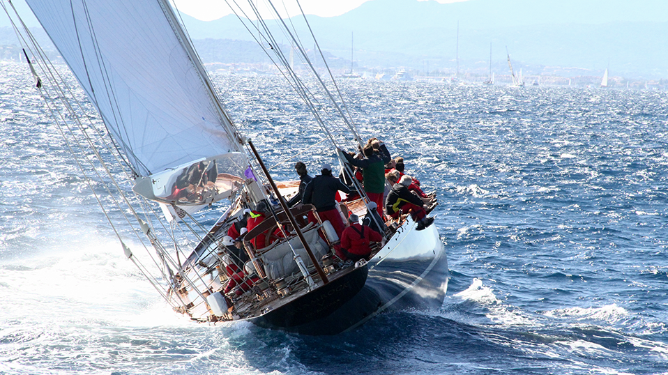 Segelboot mit Mannschaft auf hoher See bei starkem Wind, das sich zur Seite neigt.