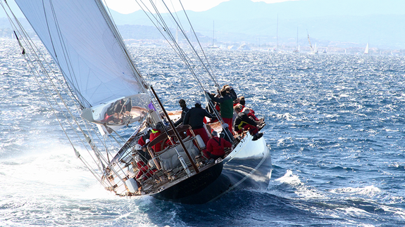 Segelboot mit Mannschaft auf hoher See bei starkem Wind, das sich zur Seite neigt.