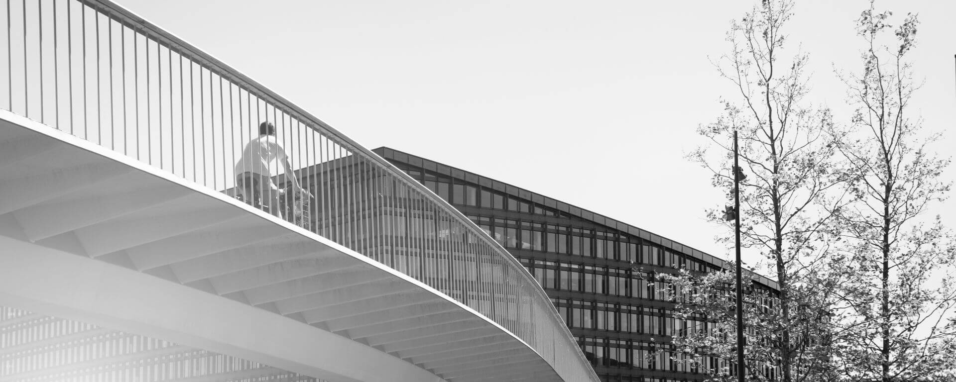 Radfahrer fährt über eine Brücke auf ein Bürogebäude zu